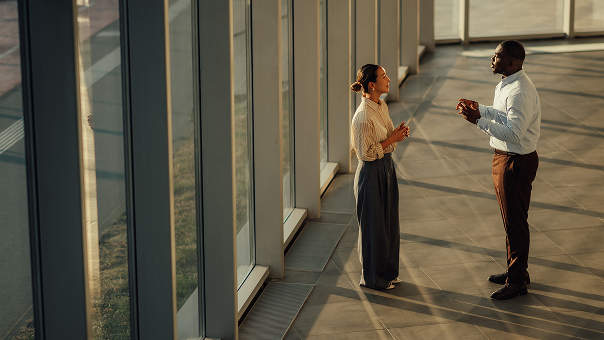 Two people talking near windows